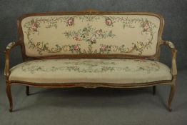 A Louis XV style French walnut canape sofa, the needlepoint upholstery with foliate designs on an