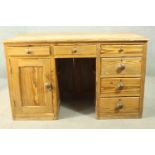 A Victorian pitch pine kneehole desk, with three short drawers, over a cupboard door to one