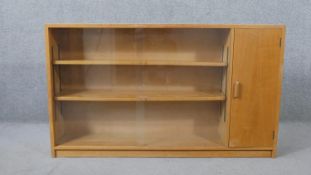 A 1960s light oak glazed Criterion bookcase, with two glass sliding doors enclosing shelves, one