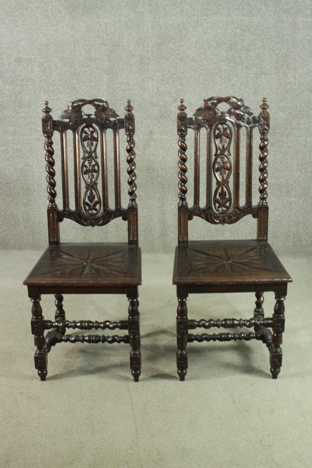 A pair of Carolean style oak side chairs, the top rail carved with vine leaves, over a carved vine