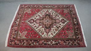 A hand made Persian Heriz carpet with central medallion on a madder field. L.201 W.158cm