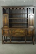 An early 20th century oak dresser, the plate rack with shelves flanked by two cupboard doors, over