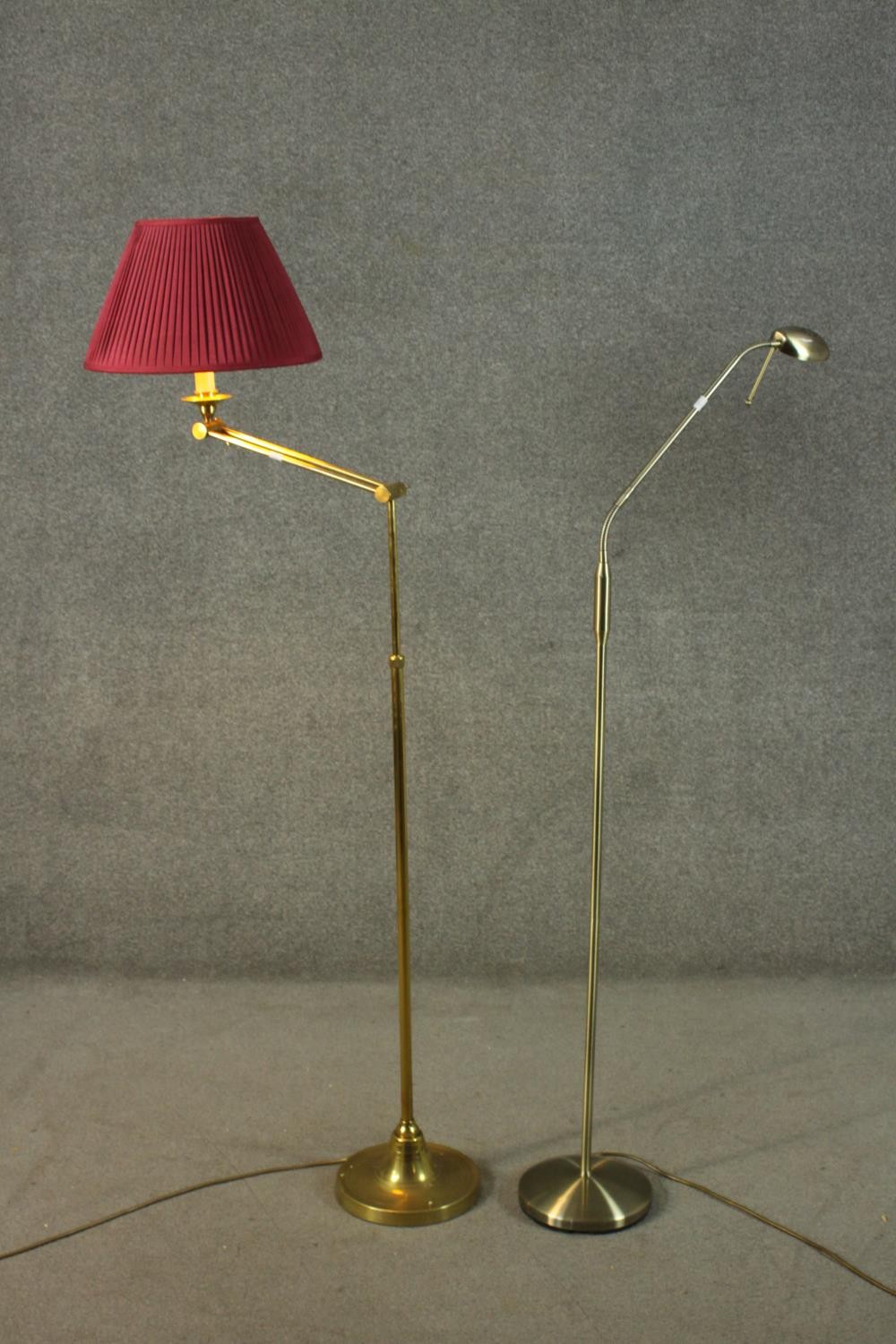 Two adjustable brass floor lamps, one with an extending arm and circular base and the other