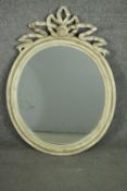 A vintage Continental grey painted and distressed oval mirror, with a carved frame and carved ribbon