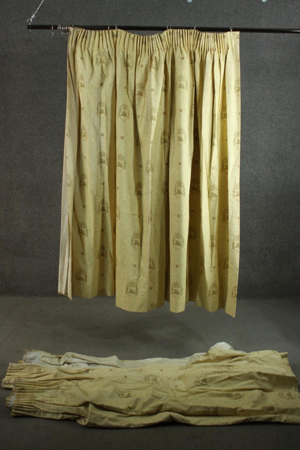 Three fully lined yellow cotton mix curtains decorated with heraldic design. H.170 W.220cm.
