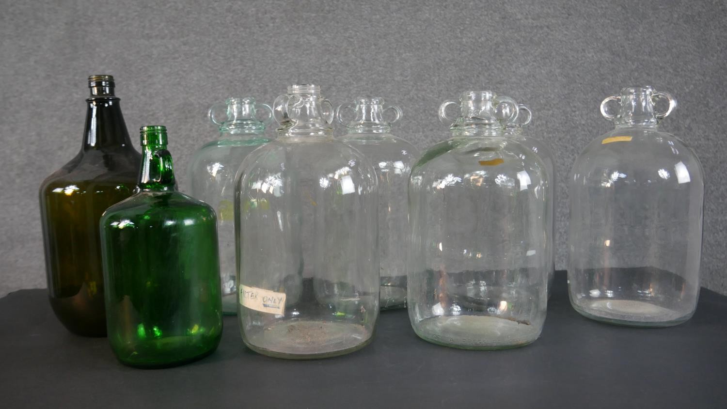 A collection of eight glass demijohns, one brown and one green glass. H.38cm (largest)