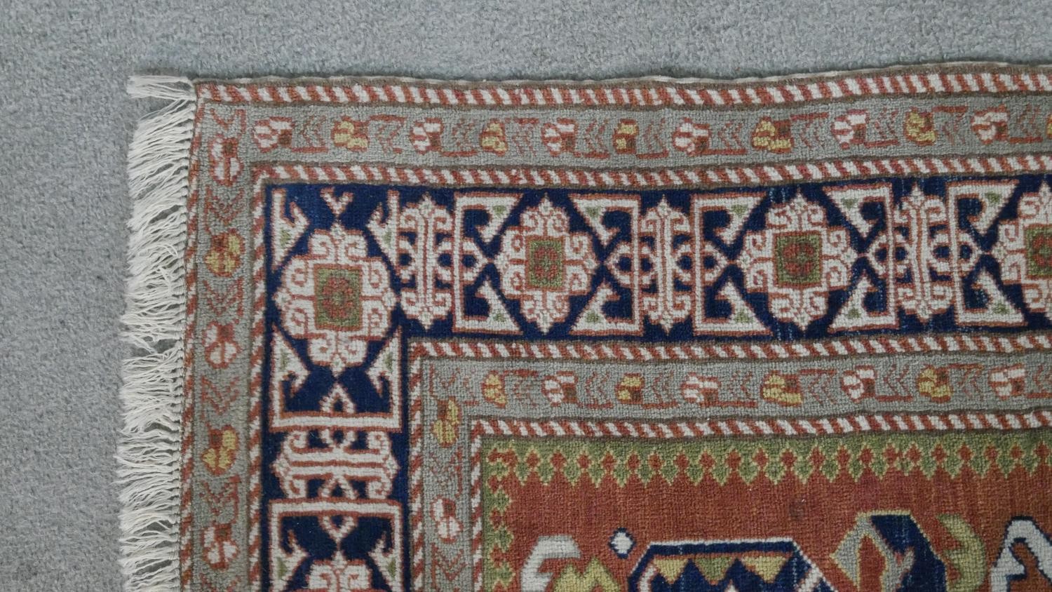 A handmade Russian Shirvan carpet with repeating stylised motifs on a pale terracotta ground - Image 4 of 7