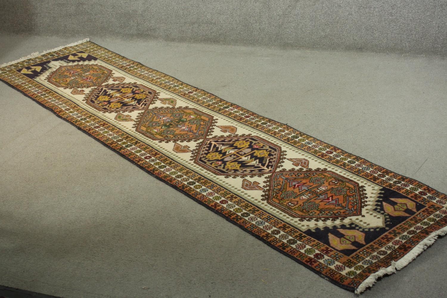 A hand made beige ground Russian Kazak runner. L.290 W.72cm.