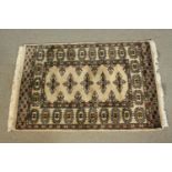 A small hand made beige ground Pakistan Bokhara rug. L.90 W.64cm.