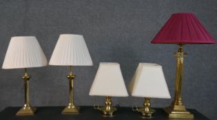 A collection of five brass table lamps, one of Corinthian column form, a pair of chamber sticks, and