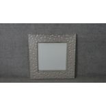 A contemporary stainless steel framed mirror, of square form, the frame cast with spherical