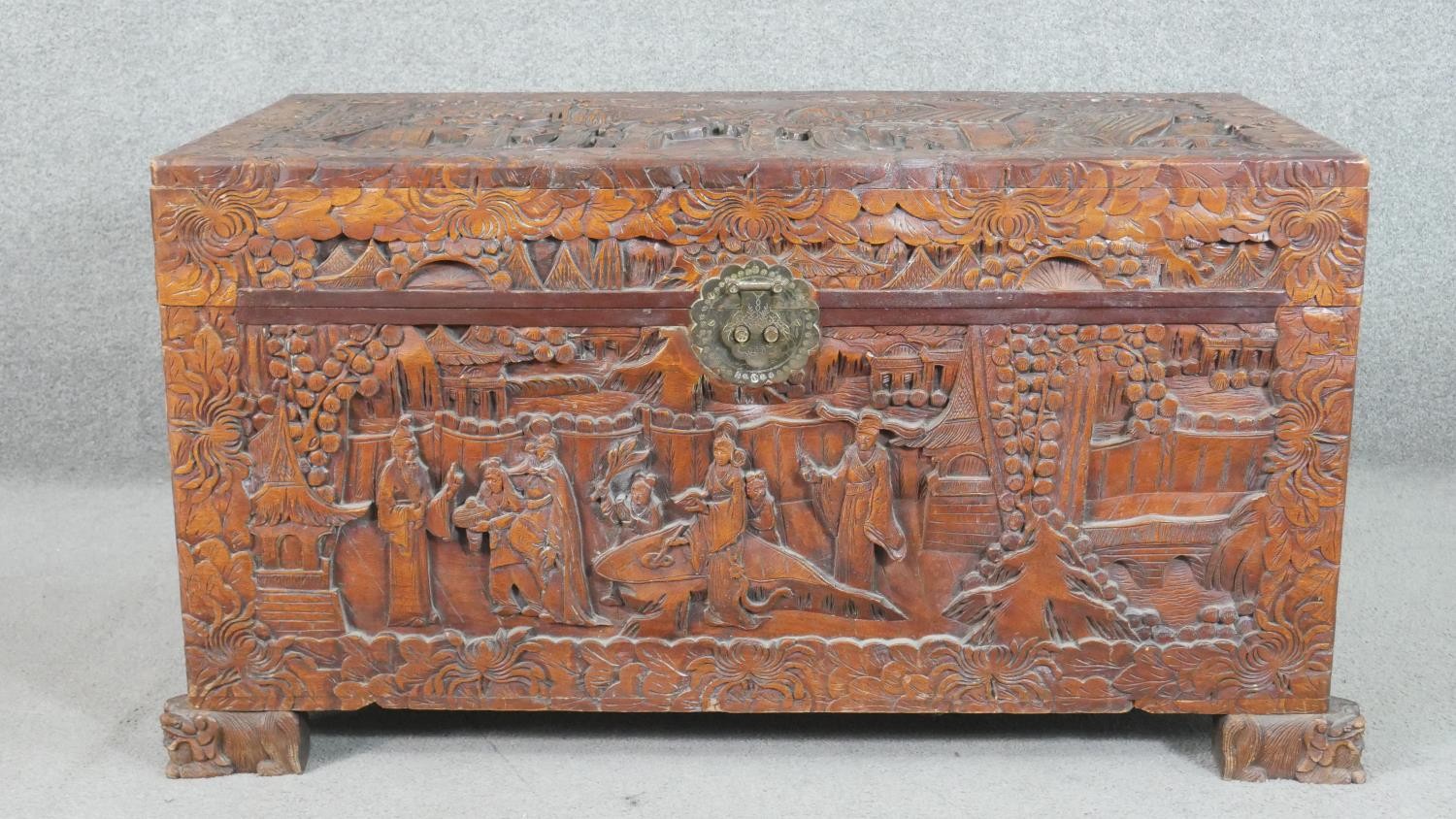 A 20th century Chinese camphorwood coffer, of rectangular form, the lid and sides ornately carved