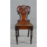 A Victorian mahogany hall chair, the carved and pierced scrolling back carved with a shield, over