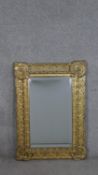 An early 20th century pressed gilt metal framed mirror, with a rectangular bevelled plate, the frame