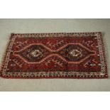 A hand made red ground Shiraz rug. L.130 W.82cm.