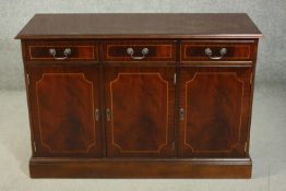 A George III style reproduction mahogany sideboard, with three short drawers over three cupboard