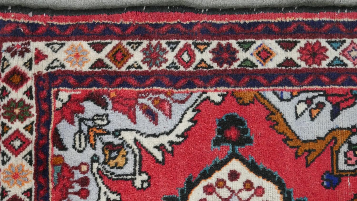 A handmade Persian Hamadan rug with repeating floral motifs across the madder ground within - Image 4 of 7