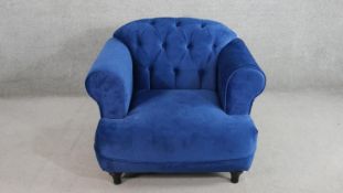 A contemporary Harto armchair, upholstered in blue suede style fabric, with a buttoned back, and