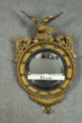 A C.1900 carved giltwood Regency design convex mirror, surmounted by an eagle, the frame with ball