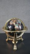 A specimen stone terrestrial desk globe, on a black ground, with a brass frame, on scrolling legs,