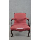 A 19th century mahogany open armchair, upholstered in crimson coloured fabric, the scrolling arms