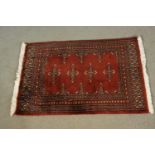 A small hand made red ground Pakistan Bokhara rug. L.90 W.64cm.