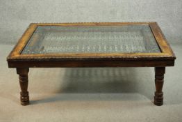 An Indian sheesham wood coffee table, of rectangular form with a plate glass top over an interlinked