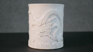 A Chinese blanc de chine relief porcelain dragon among the waves design brush pot. Impressed