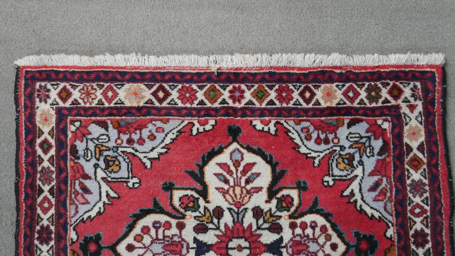 A handmade Persian Hamadan rug with repeating floral motifs across the madder ground within - Image 6 of 7