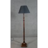 A contemporary turned fruitwood and parcel gilt standard lamp, with a pleated shade, on a square