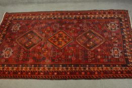 A hand made red ground Persian Qashqai carpet. L.236 W.155cm.
