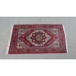 A Persian hand made Senneh rug with triple medallion on burgundy ground within spandrels and