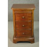 A Victorian style fruitwood bow front bedside chest, with a slide over three drawers, on a plinth