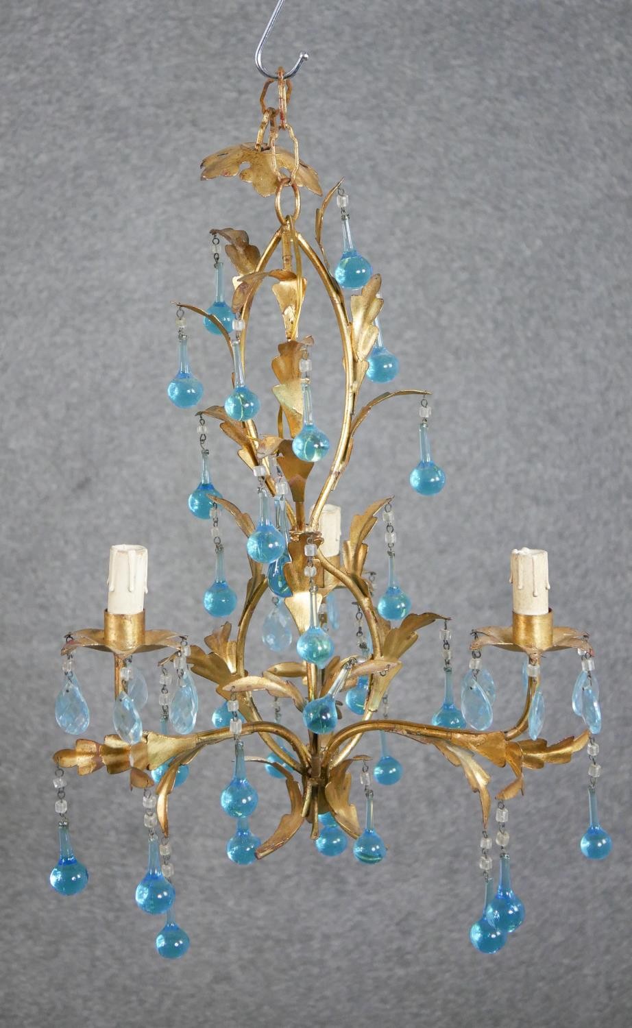 A contemorary three branch gilt metal chandelier, decorated with oak leaves, hung with blue glass