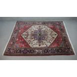 A hand made Persian Heriz carpet with central lozenge medallion on a burgundy field. H.196 W.152cm