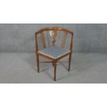 An Edwardian marquetry inlaid mahogany corner chair, upholstered in blue fabric to the seat, on