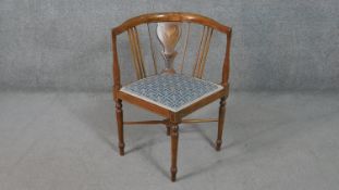 An Edwardian marquetry inlaid mahogany corner chair, upholstered in blue fabric to the seat, on
