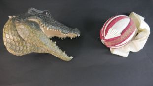 A painted fibreglass wall mounted head of an alligator plus a Indian turban hat. H.30 W.36cm (