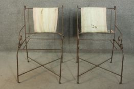 A pair of wrought iron garden armchairs, with scrolling open arms.