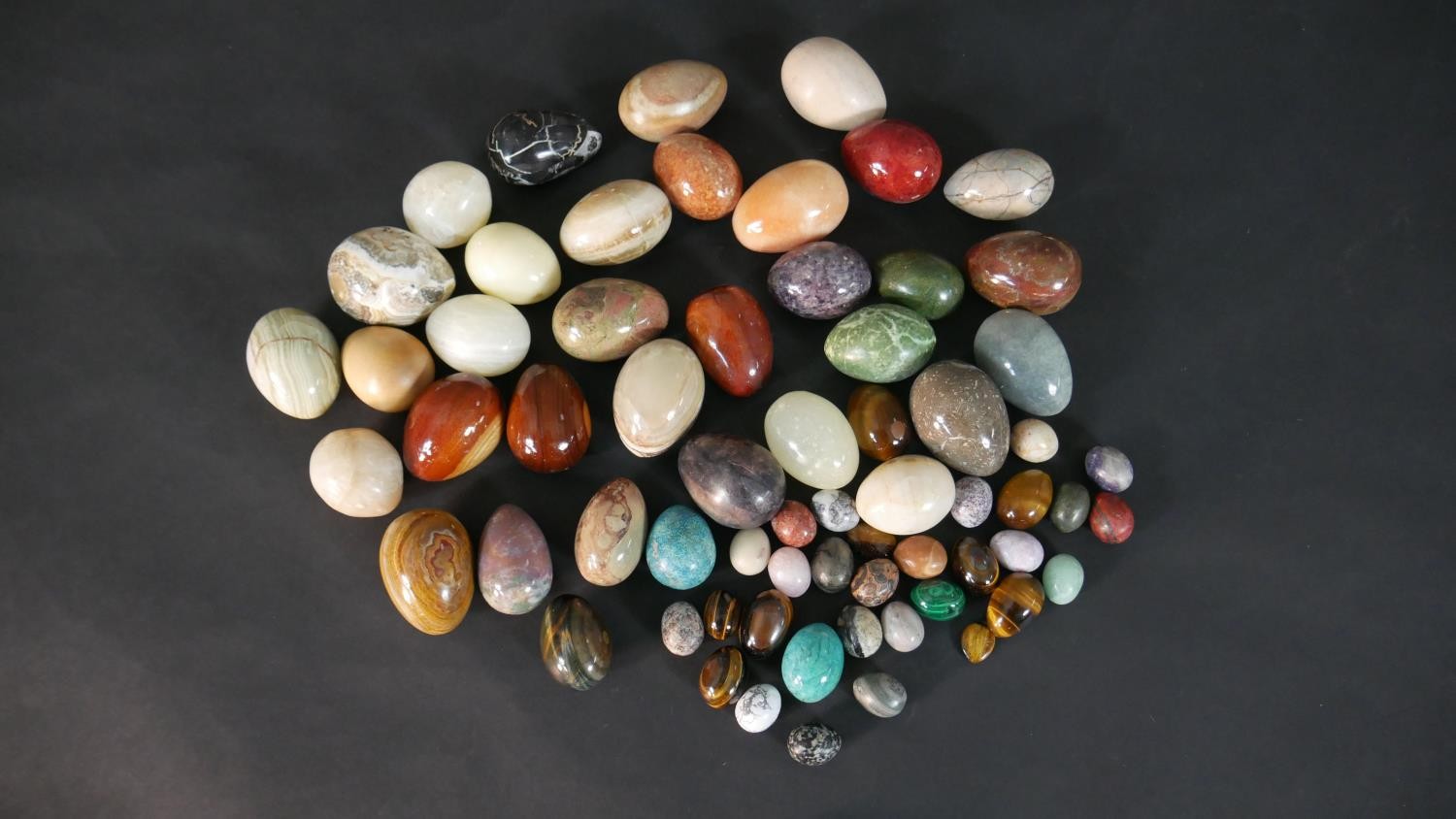 A collection of approximately sixty carved and polished gemstone and mineral eggs, various sizes.