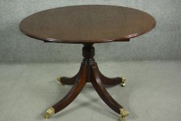 A reproduction Georgian style mahogany dining table, of circular form, with an additional leaf, on