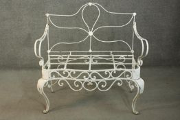 A white painted French wrought iron two seater garden bench, with open arms, on cabriole legs.