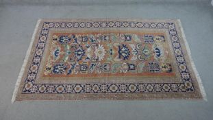 A handmade Russian Shirvan carpet with repeating stylised motifs on a pale terracotta ground
