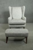 A contemporary wing back armchair and foot stool, upholstered in light grey fabric, on tapering