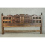 A Mexican stained pine super king size headboard, with turned finials, and a scrolling top, above