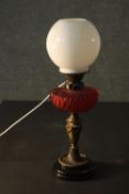 A Victorian oil lamp converted to electricity, with a spherical milk glass shade and a gadrooned red