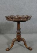 A Victorian walnut tripod table, the hexagonal tilt top with an ornately carved and pierced edge, on