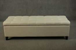 A contemporary Ottoman padded bench, upholstered in cream linen fabric, with a padded and tufted