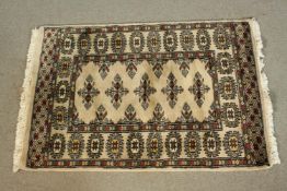 A small hand made beige ground Pakistan Bokhara rug. L.90 W.64cm.