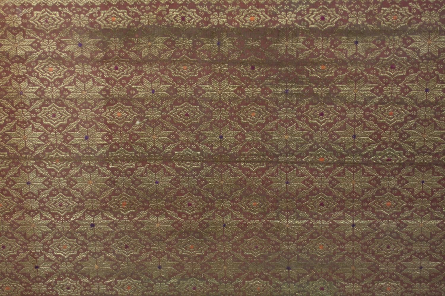 A framed and glazed Indonesian plum ground and gold thread woven silk work. H.102 W.229cm. - Image 3 of 5